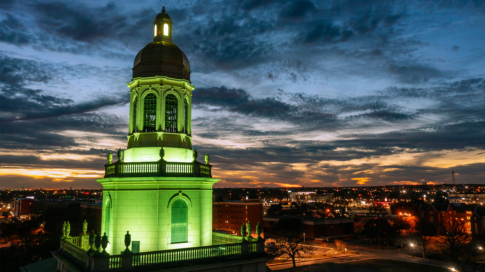 Pat Neff Hall, lit up in green, at sunset